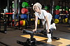 Mujer mayor realizando ejercicio de remo con mancuerna en banco plano dentro de un gimnasio